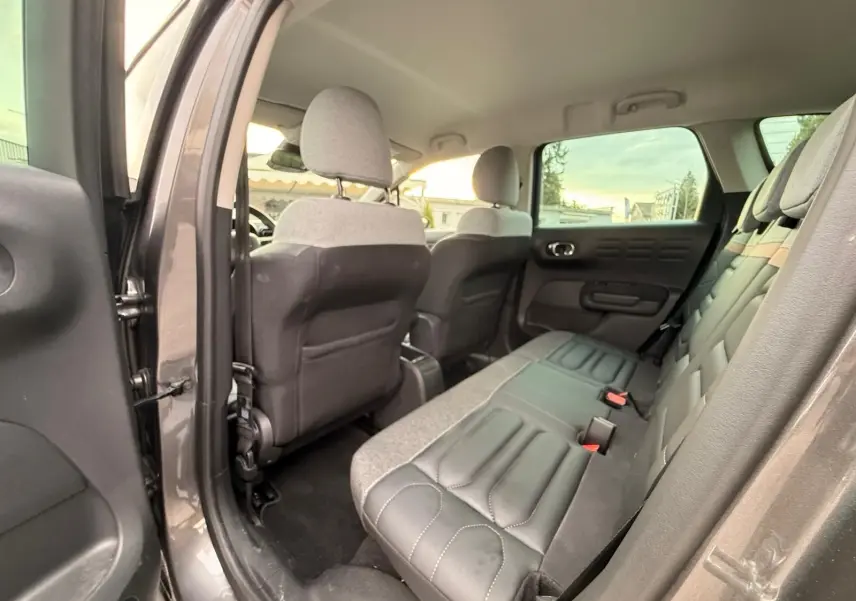 Vue intérieure arrière côté gauche de la Citroën C3 Aircross 2022 gris platinium, montrant les sièges arrière en tissu et cuir.