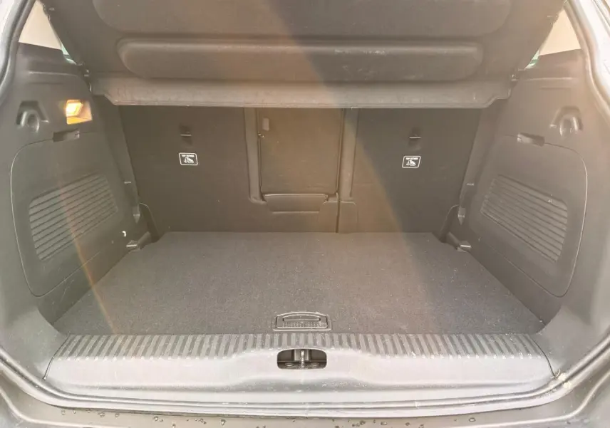 Vue intérieure du coffre spacieux et propre du Citroën C3 Aircross gris platinium, avec banquette arrière rabattue partiellement.