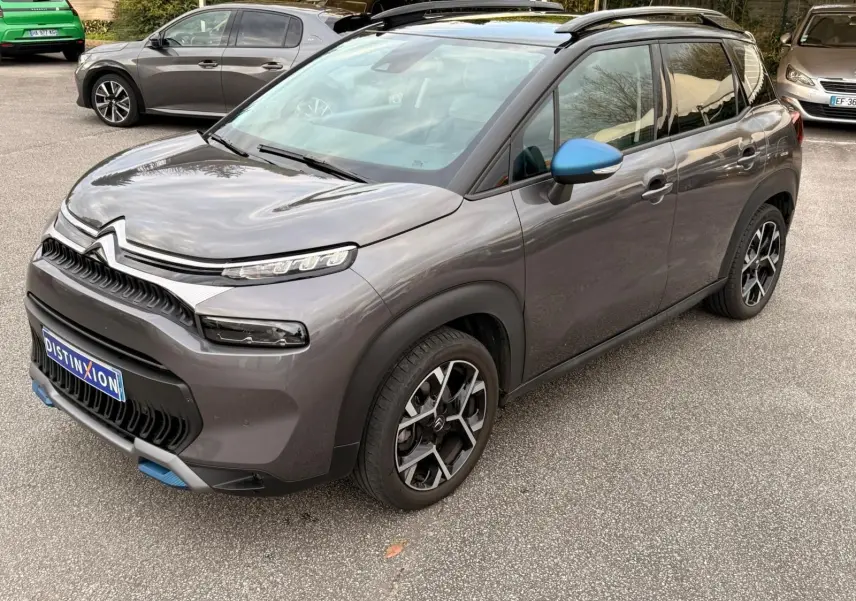 Citroën C3 Aircross gris platinium vue 3/4 avant droit, avec rétroviseur bleu et jantes noires stylées.
