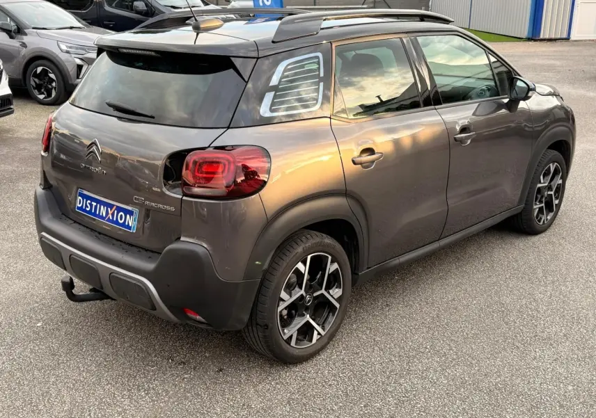 Vue 3/4 arrière droite d'un Citroën C3 Aircross gris platinium avec toit noir et jantes alliage bicolores.