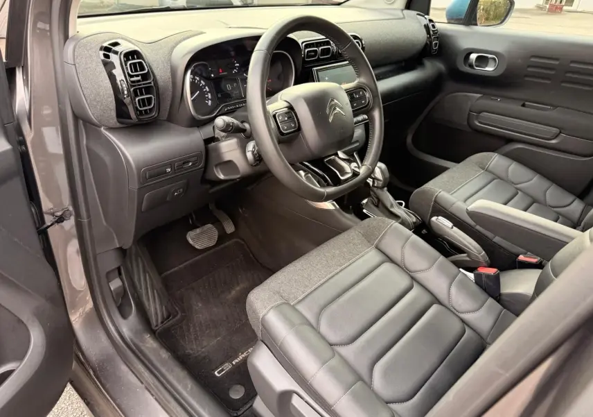 Vue intérieure côté conducteur du Citroën C3 Aircross gris platinium, montrant le tableau de bord et les sièges en cuir et tissu.