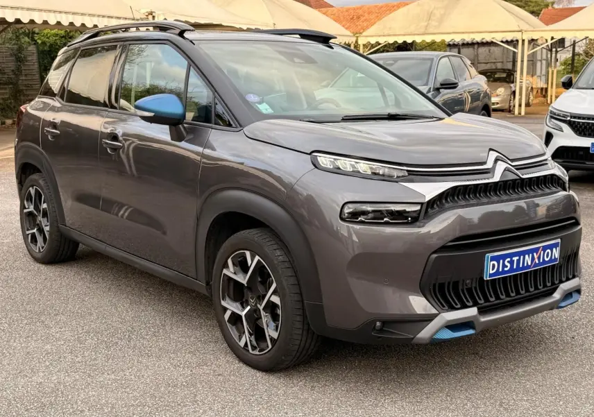 Vue 3/4 avant droite d'un Citroën C3 Aircross gris platinium avec détails bleus sur le bouclier et les rétroviseurs.