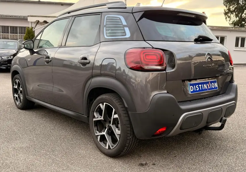 Vue 3/4 arrière droite d’un Citroën C3 Aircross gris platinium avec jantes alliage et toit noir contrasté.