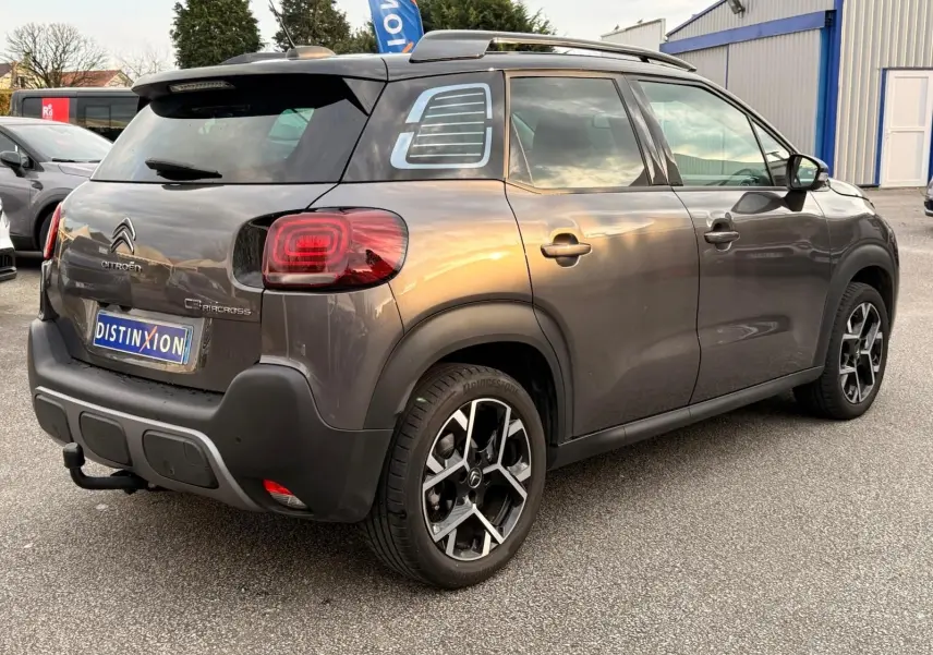 Vue 3/4 arrière droite d'un Citroën C3 Aircross gris platinium avec toit ouvrant et jantes alliage distinctives.