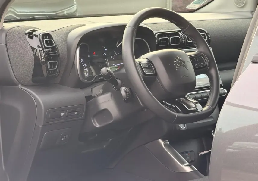 Vue intérieure côté conducteur du tableau de bord et volant noir du Citroën C3 Aircross gris platinium 2022.