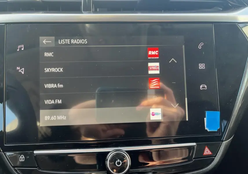 Écran tactile central de l’Opel Corsa 2022 affichant la liste des radios, avec commandes autour en finition noire brillante.
