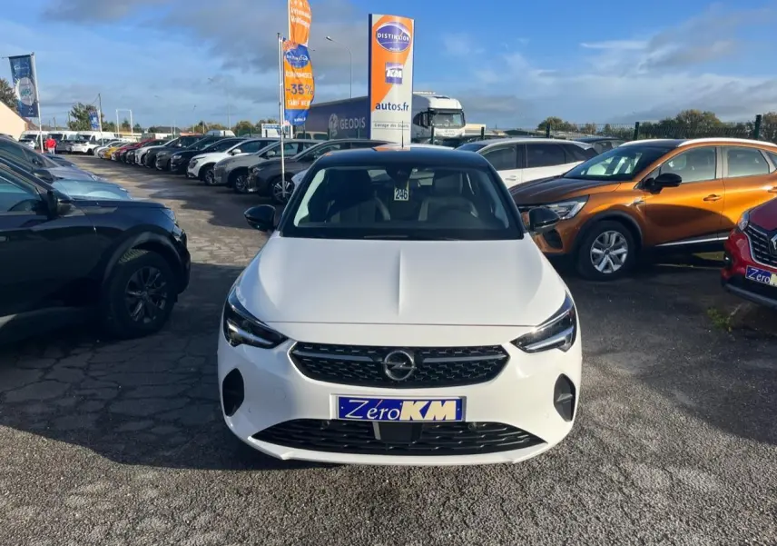 Vue avant d'une Opel Corsa blanche 2022 avec calandre noire et phares LED, stationnée en extérieur sur un parking.