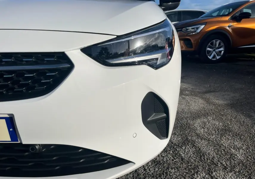 Gros plan sur l'avant droit blanc d'une Opel Corsa 2022, mettant en valeur le phare et la calandre noire.