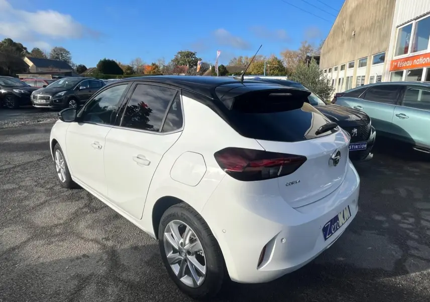 Opel Corsa blanche vue 3/4 arrière droit, toit noir, vitres arrière surteintées et rétroviseurs noirs.