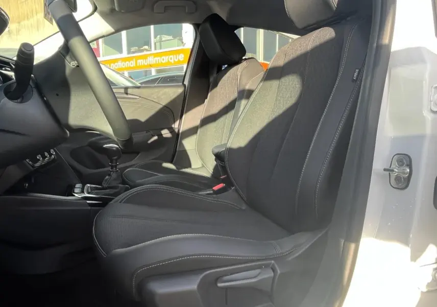 Vue intérieure côté conducteur de l’Opel Corsa blanc 2022, sièges noirs avec surpiqûres blanches visibles.