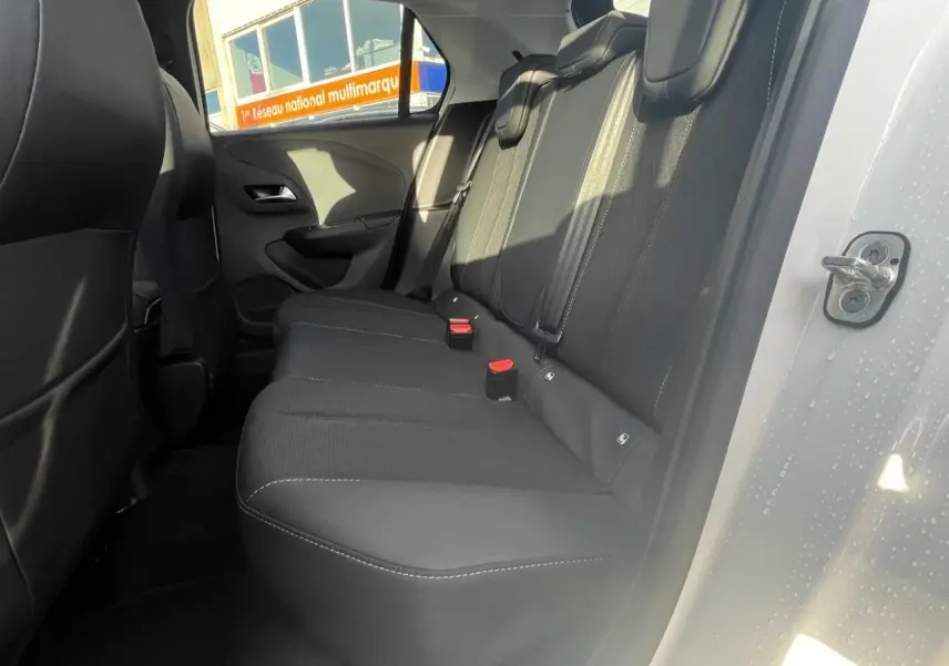 Vue intérieure de la banquette arrière noire de l’Opel Corsa blanche, porte arrière droite ouverte.