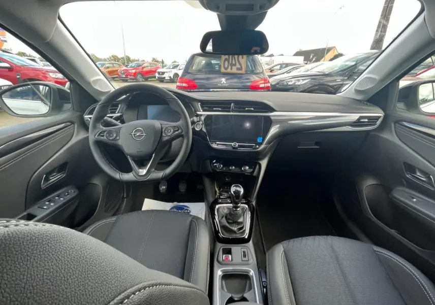 Vue intérieure avant de l’Opel Corsa blanche 2022, montrant le tableau de bord et la console centrale avec boîte manuelle.
