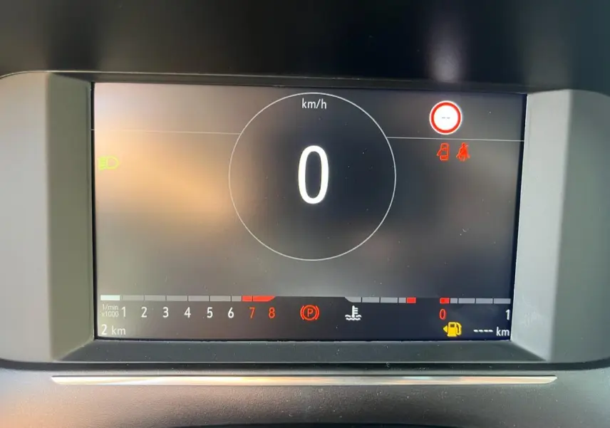 Écran digital du tableau de bord de l’Opel Corsa blanc, affichant vitesse zéro et alertes au frein à main et portières.