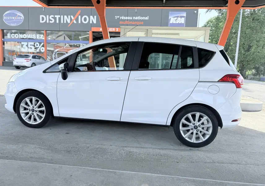 Ford B-MAX blanc vue de profil côté gauche, avec jantes alliage et portes arrière coulissantes visibles.
