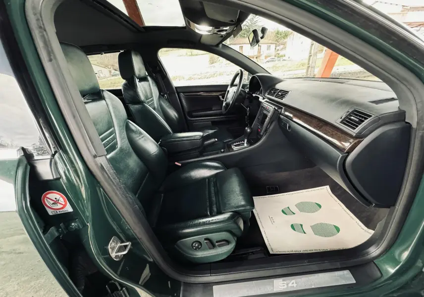 Intérieur noir cuir de l'Audi S4 Avant 2004 vu côté conducteur avec tableau de bord et sièges sport.