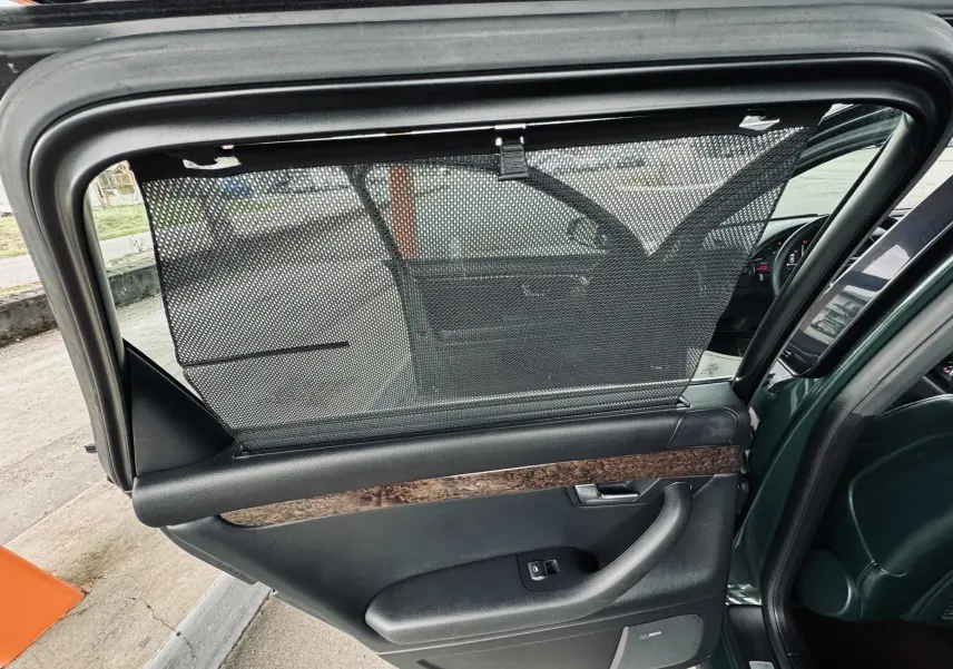 Porte arrière droite ouverte d’une Audi S4 Avant verte, avec pare-soleil en filet et garniture bois visible.