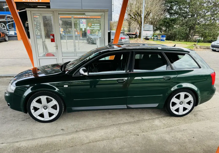 Audi S4 Avant vert vue de profil côté gauche, avec jantes argentées et toit ouvrant sous un abri orange.