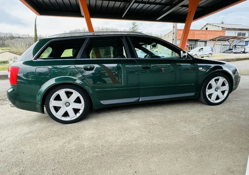 Profil côté gauche d'une Audi S4 Avant 2004 vert foncé avec jantes alliage et toit partiellement couvert.
