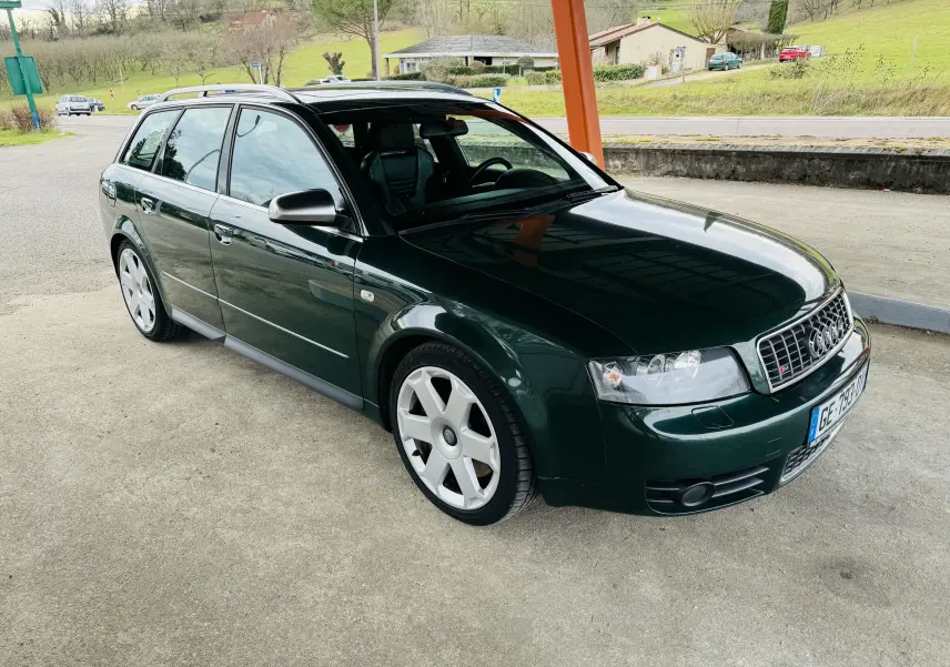 Audi S4 Avant vert foncé vue 3/4 avant droit sous abri avec jantes alliage et calandre S4 distinctive.