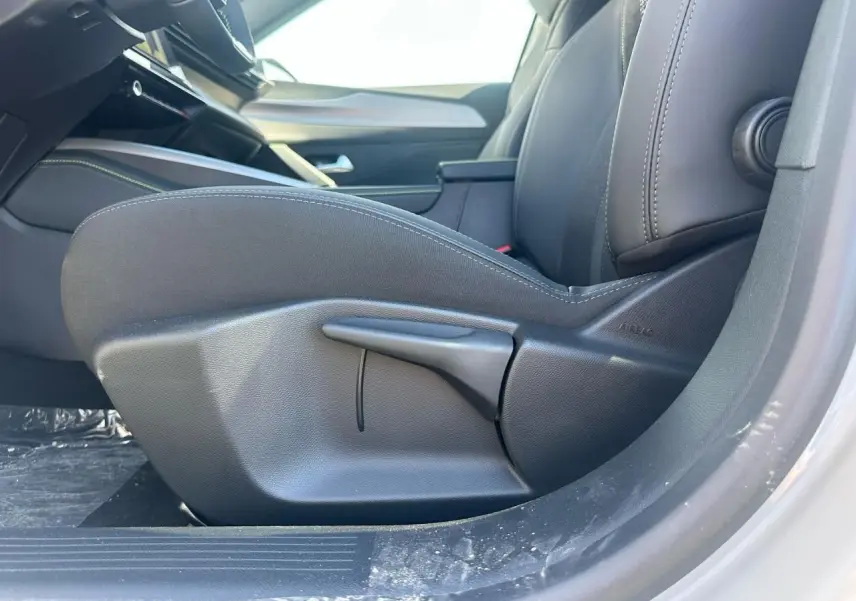 Gros plan sur le siège avant côté conducteur de la Peugeot 308 blanche Okenite, intérieur noir avec coutures visibles.