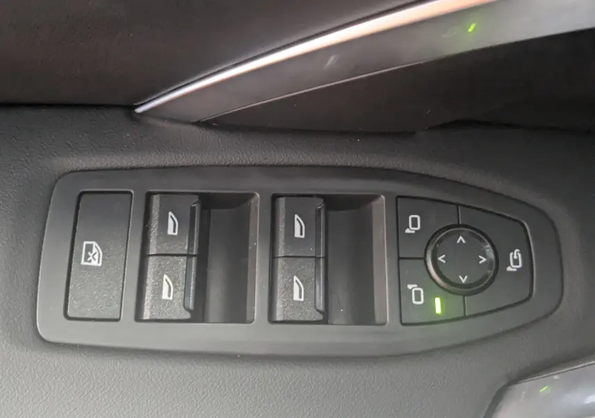 Gros plan sur les commandes des vitres et rétroviseurs côté conducteur du BMW X1 noir 2025, finition M Sport.