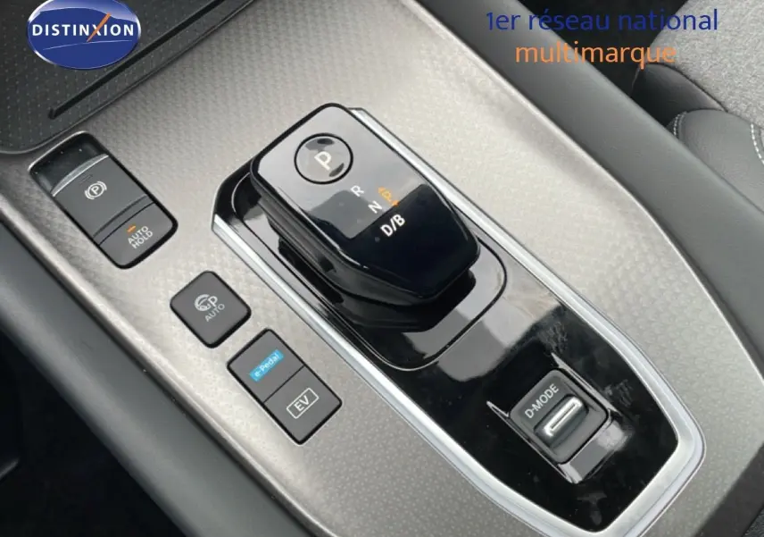 Gros plan sur la console centrale noire et grise du Nissan Qashqai blanc nacré, mettant en valeur le sélecteur de boîte automatique et les boutons de contrôle.