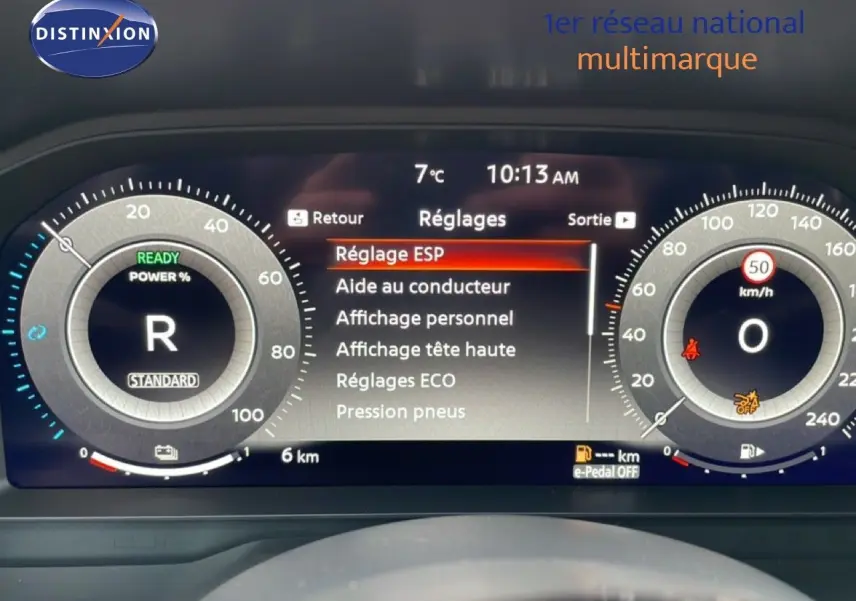 Tableau de bord numérique du Nissan Qashqai blanc nacré, affichant les réglages du véhicule et la vitesse à 0 km/h.