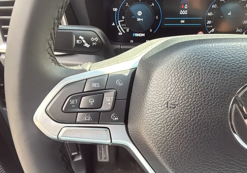 Gros plan sur le volant du Volkswagen Amarok Simple Cabine V6 240 BVA Aventura 2025 avec commandes intégrées et tableau de bord numérique.