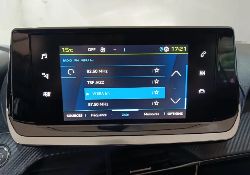 Écran tactile central de la Peugeot 208 électrique 2023 affichant la radio FM avec interface moderne et commandes digitales.