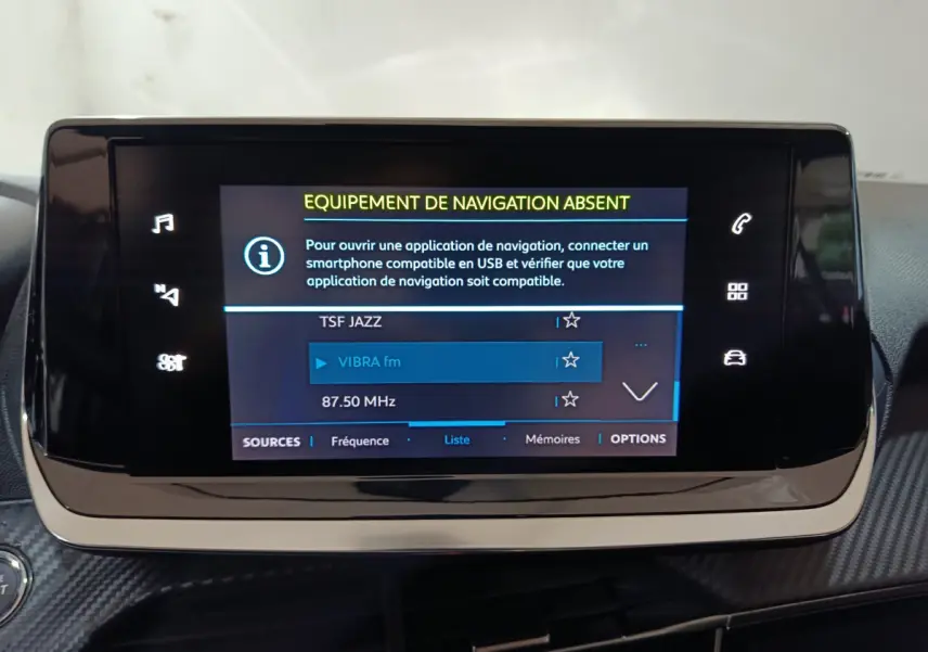 Écran tactile central de 7 pouces du tableau de bord de la Peugeot 208 électrique blanche, affichant les options radio.