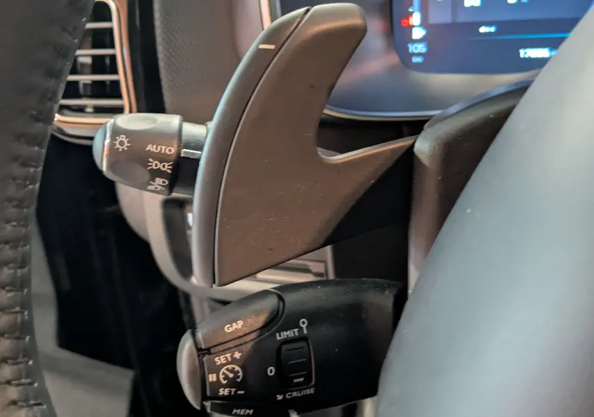 Gros plan sur les palettes de changement de vitesse et commandes au volant du Citroën C5 Aircross hybride noir 2025.