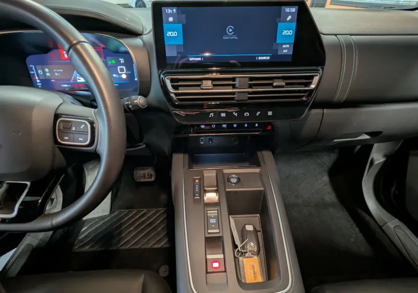 Vue intérieure centrée sur la console et le volant du Citroën C5 Aircross hybride 2025 avec écran tactile et clé posée.