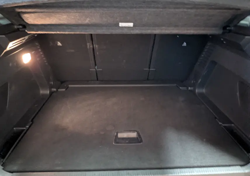 Vue intérieure du coffre noir du Citroën C5 Aircross Hybride 2025, éclairage latéral allumé, espace de rangement vide.