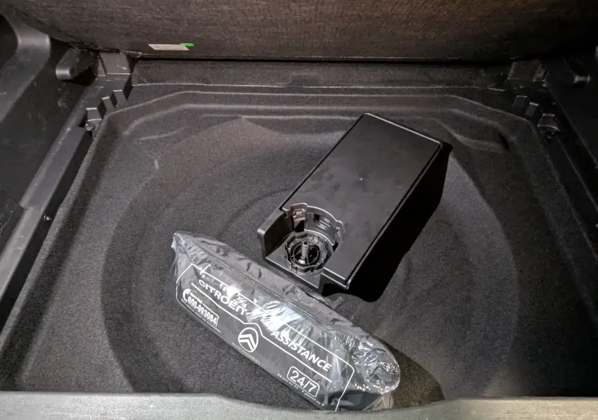 Coffre ouvert du Citroën C5 Aircross hybride noir 2025, vue plongeante sur rangement avec kit assistance emballé.