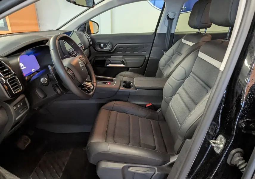 Vue intérieure côté conducteur du Citroën C5 Aircross hybride noir 2025, sièges tissu noir et tableau de bord digital.