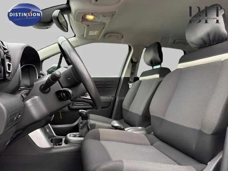 Vue intérieure côté conducteur de la Citroën C3 Aircross 2018 avec sièges tissu gris et volant cuir noir.