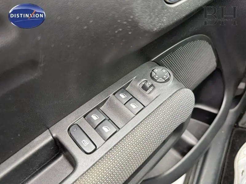 Gros plan sur les commandes des vitres électriques et rétroviseurs côté conducteur du Citroën C3 Aircross blanc, avec tissu gris.