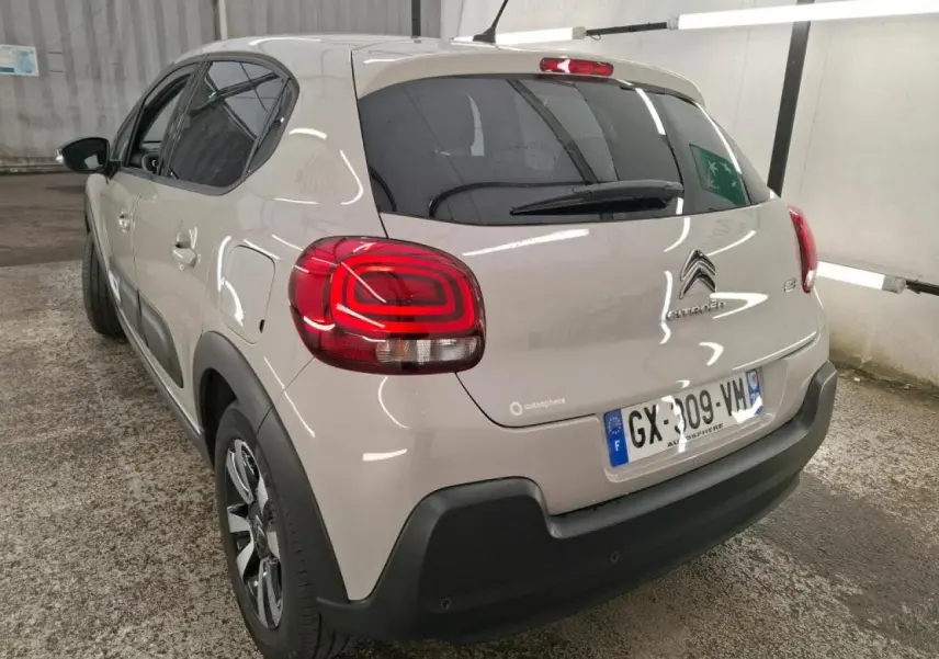 Vue 3/4 arrière gauche d'une Citroën C3 beige clair avec feux arrière LED et protections noires sur les bas de caisse.