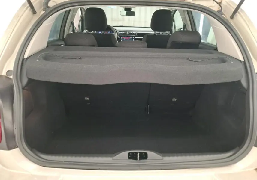 Vue arrière ouverte du coffre d'une Citroën C3 beige clair 2024, avec banquette arrière et tablette cache-bagages visibles.