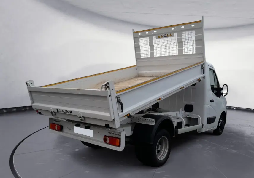 Renault Master blanc vue 3/4 arrière droit avec benne basculante relevée dans un studio.