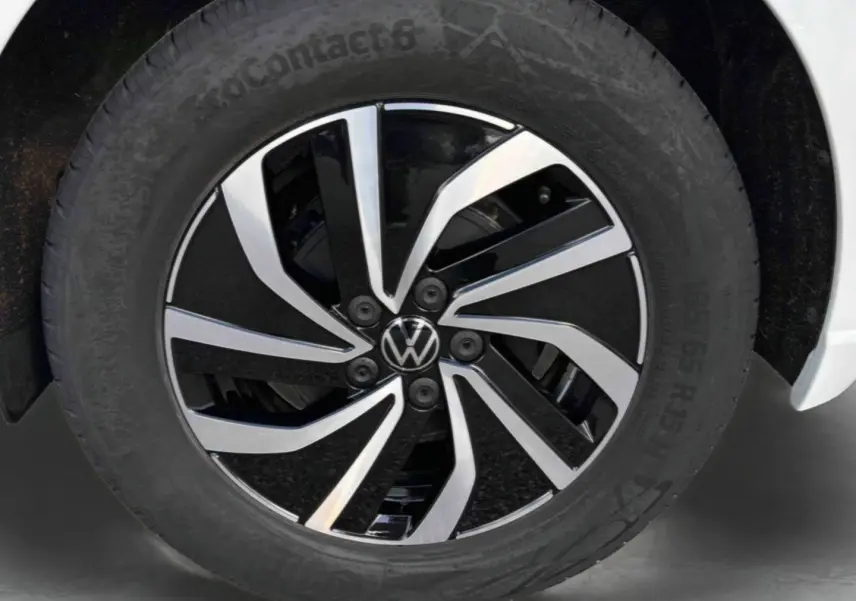 Gros plan sur la jante alliage 15 pouces bicolore noire et argentée d’une Volkswagen Polo blanche, pneu 185/65 R15 visible.