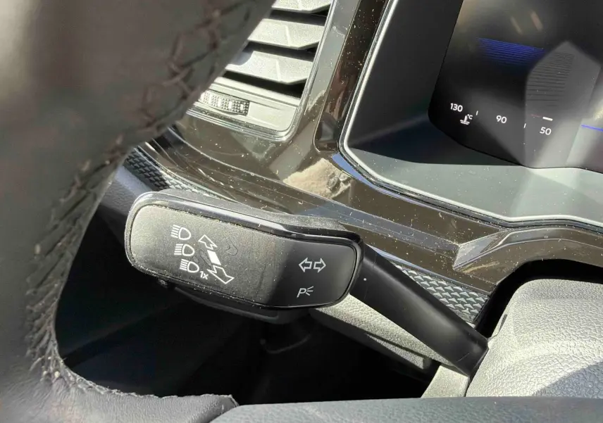 Gros plan sur la manette de clignotants à gauche du volant dans l’habitacle d’une Volkswagen Polo blanche.