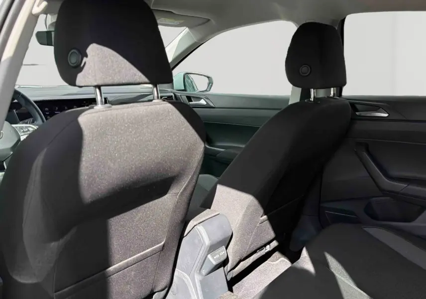 Vue intérieure arrière montrant les sièges avant noirs et la console centrale d'une Volkswagen Polo blanche 2025.