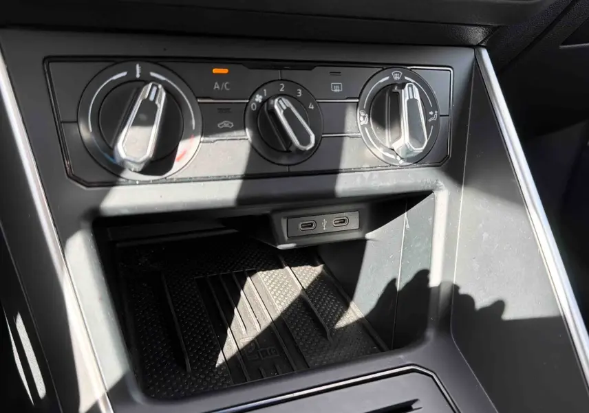 Gros plan sur les commandes de climatisation et les ports USB-C du tableau de bord d’une Volkswagen Polo blanche.
