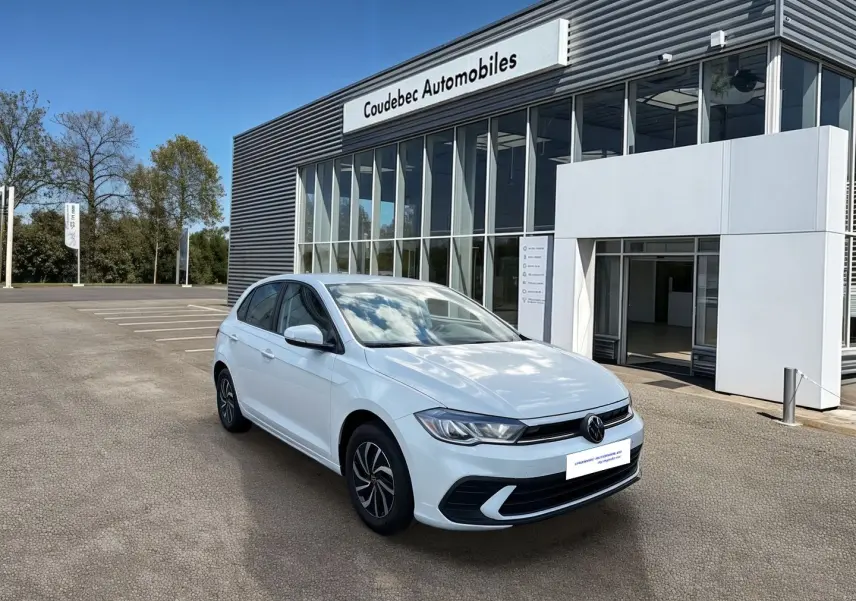 Volkswagen Polo blanche vue 3/4 avant droit devant un bâtiment de concession Coudebec Automobiles.