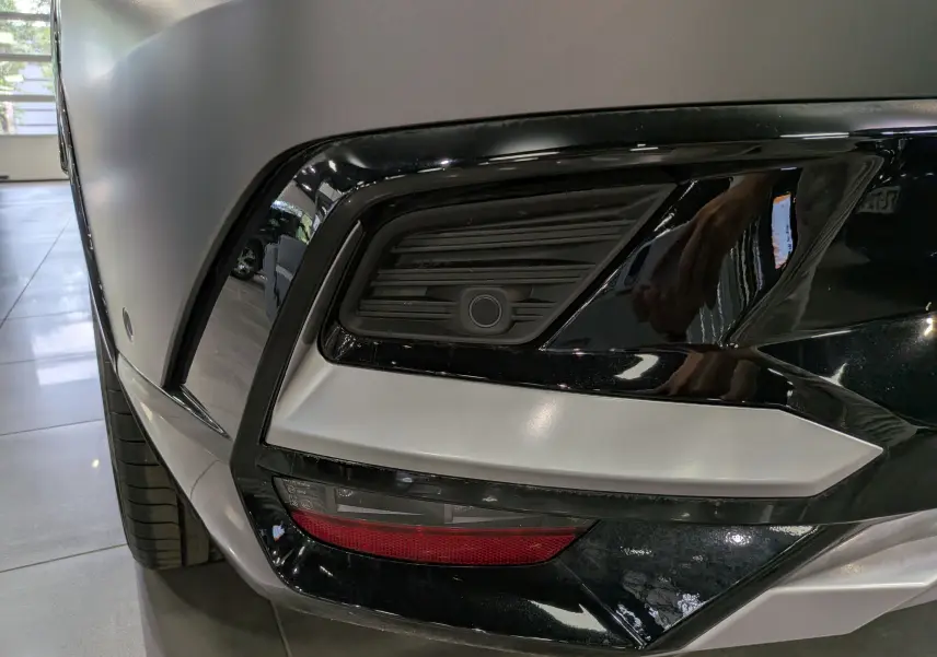 Gros plan sur le pare-chocs avant droit gris schiste satin du Renault Rafale avec détails noirs brillants et feu antibrouillard.