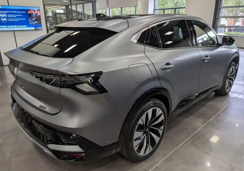 Vue 3/4 arrière droite d'une Renault Rafale E-Tech gris schiste satin avec jantes bicolores et vitres teintées en showroom.