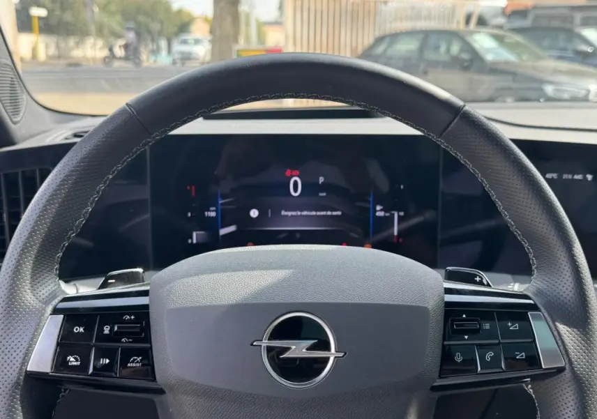 Vue rapprochée du volant gris de l’Opel Astra 2024 Diesel avec commandes intégrées et tableau de bord numérique.