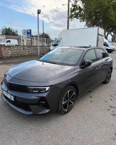 Opel Astra 1.5 Diesel gris vue 3/4 avant droit, avec jantes noires et calandre moderne, stationnée en extérieur.