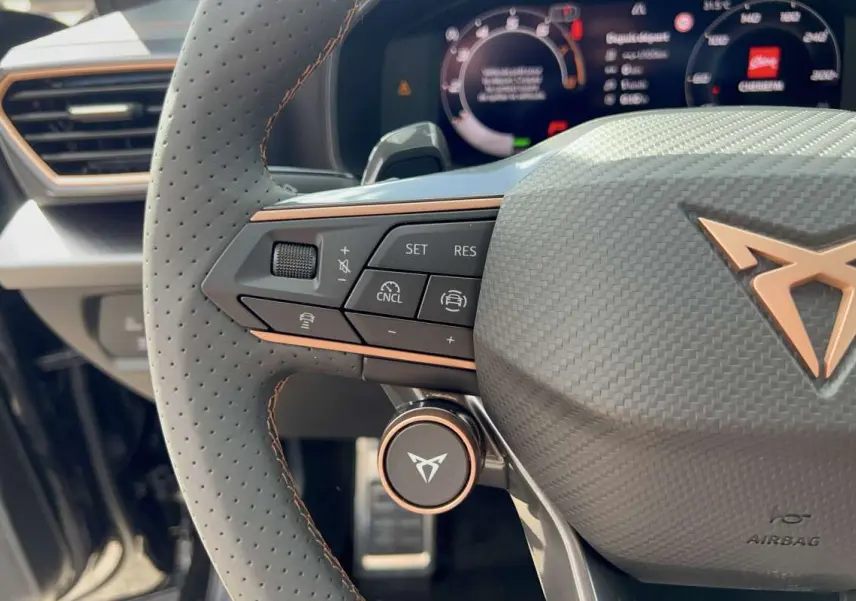 Gros plan sur le volant cuir perforé côté gauche de la CUPRA Formentor noir minuit avec commandes multifonctions et logo cuivre.